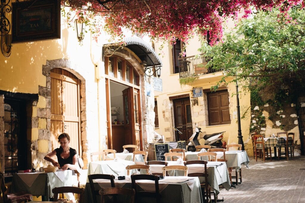 A woman sits alone eating a meal at a beautiful outdoor European restaurant. Culture-focused travel builds autonomy and discipline which are valuable life skills